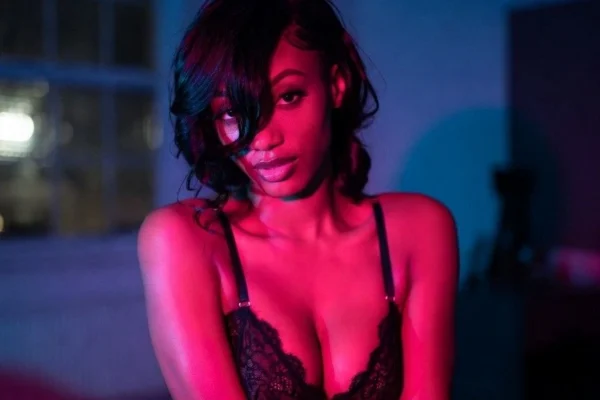 Seductive ebony woman in lace lingerie under pink blue lights