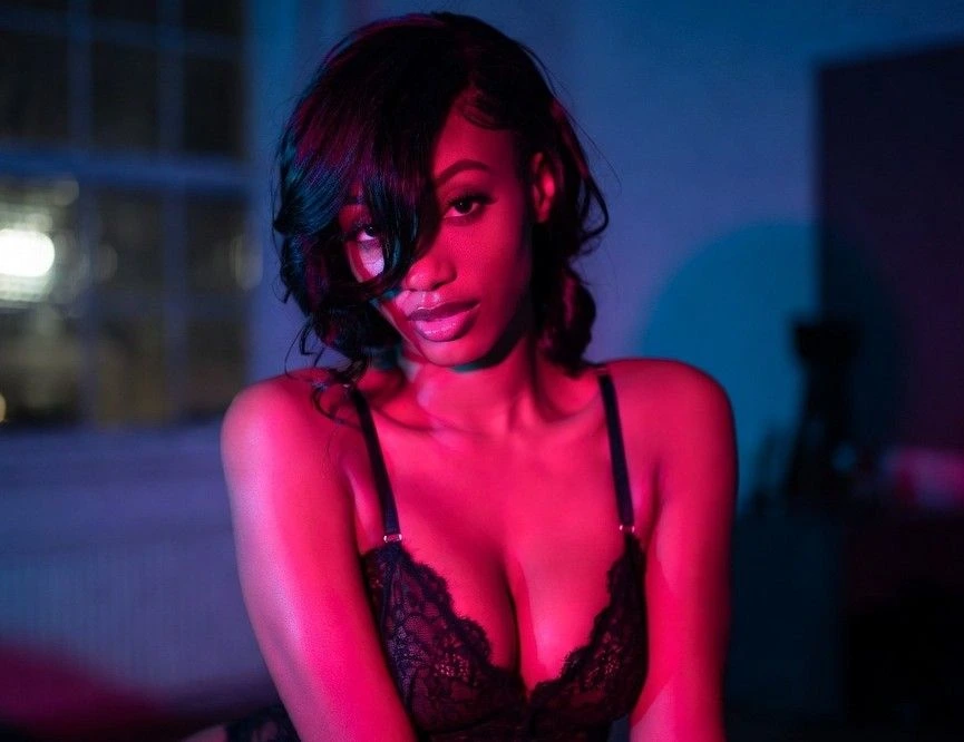 Seductive ebony woman in lace lingerie under pink blue lights